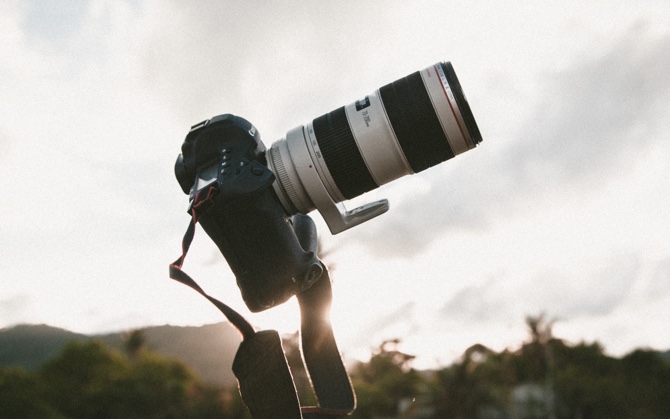 A DSLR with a telephoto lens on a tripod at golden hour.
