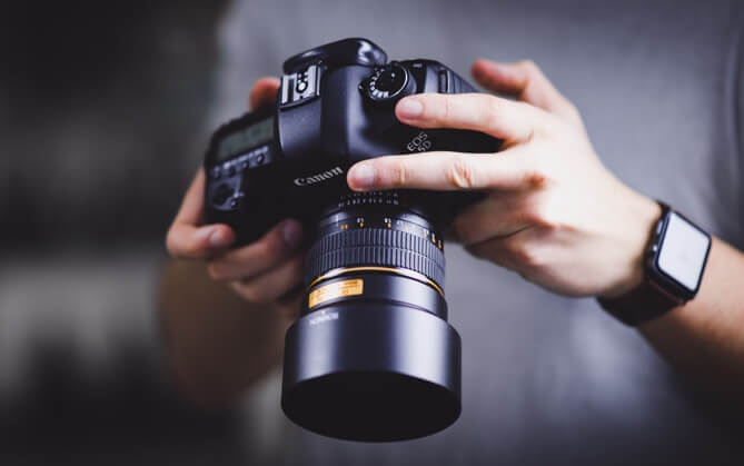 Hands holding a DSLR camera.